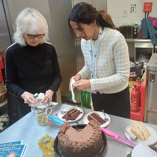 Two woman serving large chocolate cake